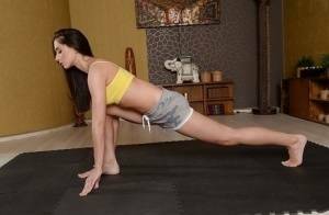 Cute brunette babe Aruna Aghora doing yoga in shorts and bare feet on girlsabc.com